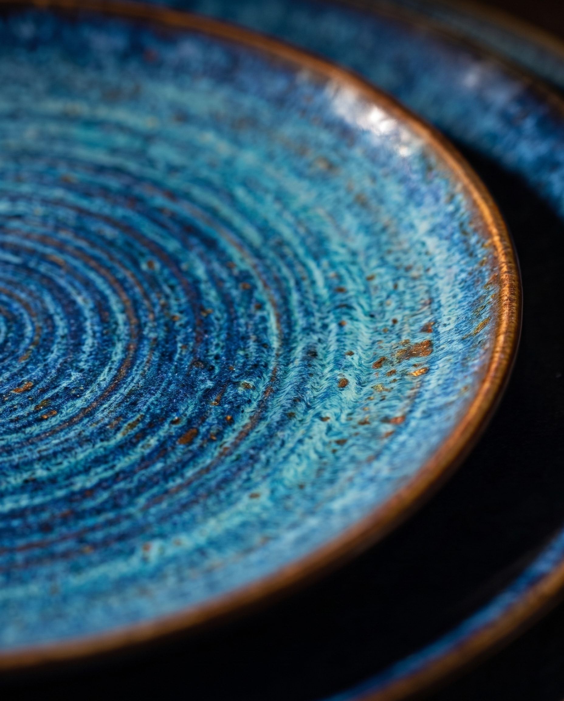 Close view of the NEELĀ glaze: throwing rings from cobalt to turquoise, flecked with iron, meeting a brown rim